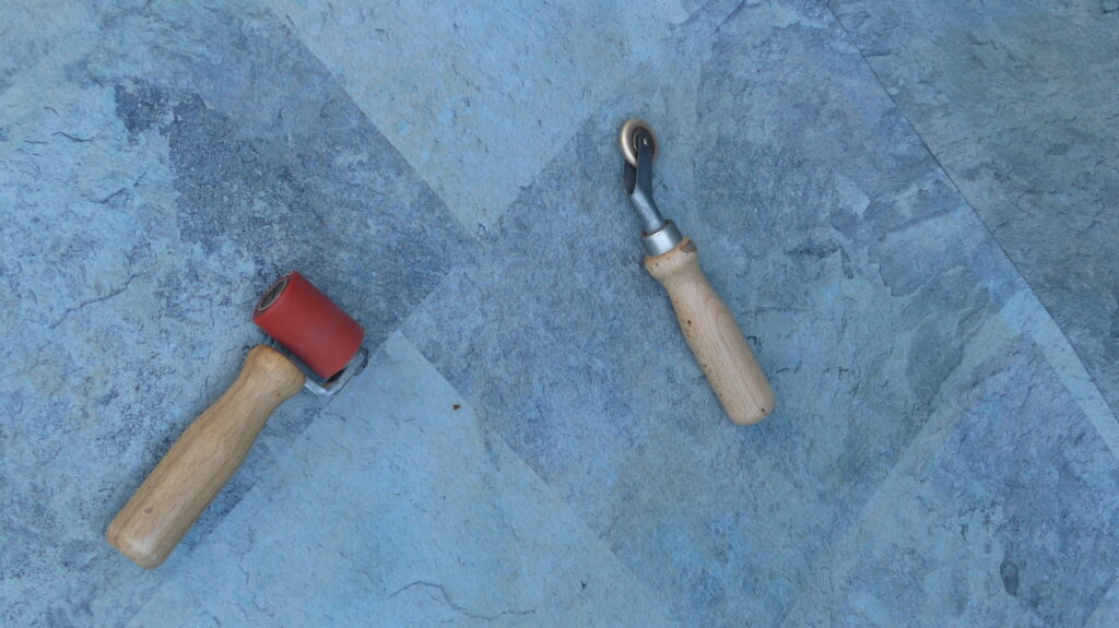 Rodillo de presión y herramienta manual utilizados durante la soldadura de lámina armada en una piscina.